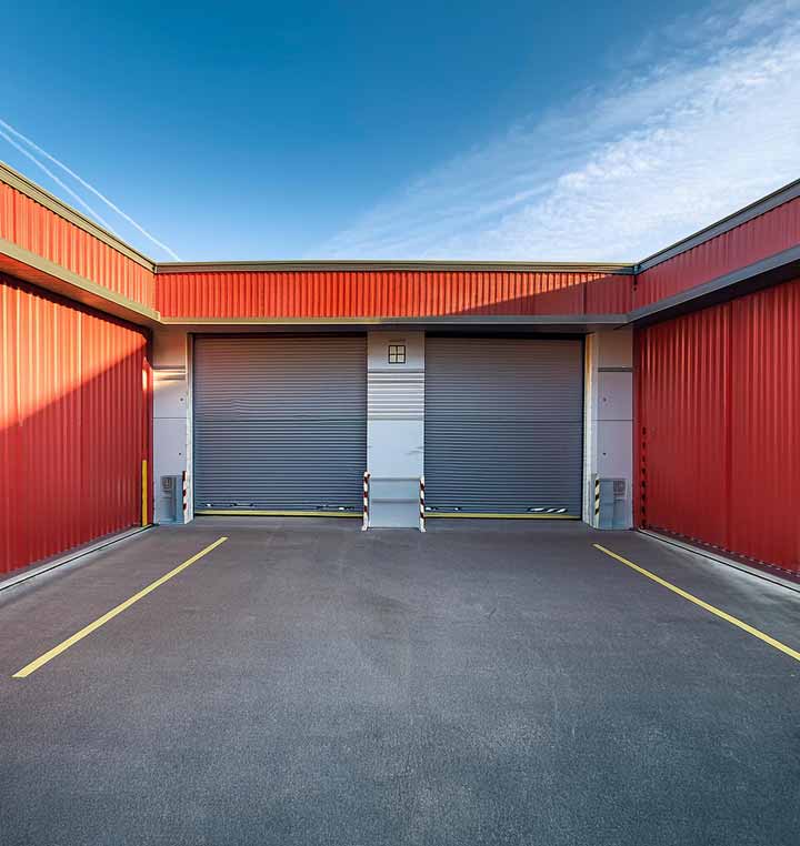 2 commercial garage doors with orange siding on both sides of area leading up to them